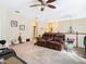 Spacious living room area with a brown leather sofa and ceiling fan at 11175 Hyde St, Weeki Wachee, FL 34614