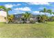 Large backyard with a green lawn, palm trees, and a screened-in lanai at 7048 White Willow Ct, Sarasota, FL 34243