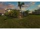 Backyard view showing the screened-in lanai, mature tropical landscaping, and grassy lawn at 7048 White Willow Ct, Sarasota, FL 34243