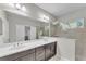 Ensuite bathroom boasts double sinks, a large mirror, and a tiled glass shower at 7048 White Willow Ct, Sarasota, FL 34243