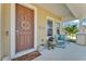Charming front porch with seating, plants, and a decorative wreath on the brown front door at 7048 White Willow Ct, Sarasota, FL 34243