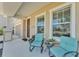 Inviting front porch with blue chairs, a small table, and potted plants at 7048 White Willow Ct, Sarasota, FL 34243