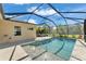 A refreshing screened-in pool features a shallow end, fountains, and a sun deck with lounge chairs, all under a blue sky at 7048 White Willow Ct, Sarasota, FL 34243