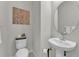 Modern powder room features a pedestal sink, decorative wall art, and a toilet at 7048 White Willow Ct, Sarasota, FL 34243