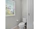 Compact powder room featuring a toilet and a window offering natural light at 7048 White Willow Ct, Sarasota, FL 34243