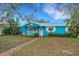 Charming blue cottage-style home with white trim, an American flag and a brick walkway to the front door at 1000 Michigan Blvd, Dunedin, FL 34698