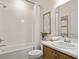 Bright bathroom features a tub with white tile surround and wood vanity with marble countertop at 2432 White Ladyfish Rd, Wimauma, FL 33598