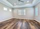 Main bedroom featuring tray ceilings, shuttered windows, hardwood flooring, and ceiling fan at 2932 Sky Blue Cv, Bradenton, FL 34211