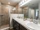 Modern bathroom featuring double sinks, granite countertops, and a tiled walk-in shower at 6022 Mangrove Creek Rd, Wimauma, FL 33598