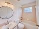 Bathroom with a shower and tub combo, round mirror, vanity sink, and natural lighting at 10760 S County Road 39, Lithia, FL 33547