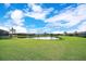 Large grassy backyard with a peaceful pond surrounded by well-maintained landscaping and other homes at 6914 Quiet Creek Dr, Bradenton, FL 34212