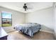 Cozy bedroom with neutral walls, ceiling fan, and a window with green outdoor views at 6914 Quiet Creek Dr, Bradenton, FL 34212
