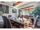 Formal dining area featuring a set table, hardwood floors and beams, with a connecting living room area at 6914 Quiet Creek Dr, Bradenton, FL 34212