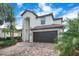 Stunning exterior view of a two-story home with a dark garage and brick driveway at 6914 Quiet Creek Dr, Bradenton, FL 34212