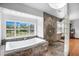 Bathroom with a luxurious soaking tub, pebble accents, and a serene view of the outdoors at 8922 Pritcher Rd, Lithia, FL 33547