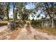 Tree-lined dirt driveway leading to property, framed by rustic wooden fences and foliage at 8922 Pritcher Rd, Lithia, FL 33547