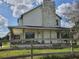 Side view of a two-story home with a stone chimney and inviting wrap-around porch at 8922 Pritcher Rd, Lithia, FL 33547