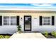 Welcoming entryway with a modern black glass front door, decorative shutters, and lush landscaping at 1046 Lee St, Englewood, FL 34224