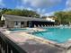 Community pool and hot tub with lounge chairs and a building in the background at 3232 Lake Pine E Way # G1, Tarpon Springs, FL 34688