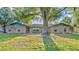 Welcoming brick home with blue shutters nestled among mature trees, enhancing its serene setting and charm at 4142 El Shaddiai Sq, Plant City, FL 33565