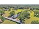 Aerial view of a beautiful home nestled among mature trees on a vast green property at 4910 Thonotosassa Rd, Plant City, FL 33565