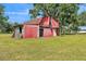 Rustic red barn featuring sliding doors and a sturdy structure, set in a grassy field under a blue sky at 4910 Thonotosassa Rd, Plant City, FL 33565