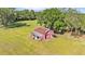 Aerial view of a charming red barn surrounded by lush greenery, showcasing the property's rustic appeal at 4910 Thonotosassa Rd, Plant City, FL 33565