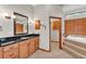 Bathroom featuring granite countertops, oak cabinetry, and a soaking tub area with tile steps and wood shutters at 4910 Thonotosassa Rd, Plant City, FL 33565