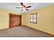 Bright bedroom features a ceiling fan, carpet floors, and shuttered windows at 4910 Thonotosassa Rd, Plant City, FL 33565