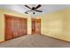 Bedroom features a ceiling fan, carpet, and a closet with paneled doors at 4910 Thonotosassa Rd, Plant City, FL 33565