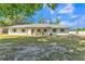 Charming single-story home featuring a painted brick facade, covered porch, and a well-maintained front yard with mature trees at 4910 Thonotosassa Rd, Plant City, FL 33565