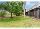 Expansive backyard features mature trees, lush lawn, and a serene view of the adjacent pond and screened in porch at 2125 Wild Grape Pl, Riverview, FL 33578