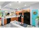 Open kitchen with wood cabinetry, black appliances, subway tile backsplash, and a pass-through to the living area at 2125 Wild Grape Pl, Riverview, FL 33578