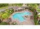 Aerial view of a pristine community pool with lounge chairs, palm trees, and beautiful landscaping at 2125 Wild Grape Pl, Riverview, FL 33578
