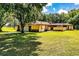 Exterior showcasing lush greenery, ample lawn space, stucco walls, a screened patio, and an attached garage at 4101 N Forbes Rd, Plant City, FL 33565