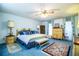 A bright main bedroom features a ceiling fan, blue carpet, and beautifully crafted wooden furniture at 4101 N Forbes Rd, Plant City, FL 33565