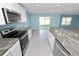 Kitchen with stainless appliances, granite countertops, island and sliding doors to backyard at 8009 Sail Clover Ln, Zephyrhills, FL 33540