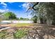 Backyard view featuring a pool, grassy area, mature trees, and a privacy fence, perfect for outdoor activities at 1411 Fernwood Pl, Seffner, FL 33584