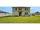 Large grassy backyard, complemented by the home's exterior with an access door and large windows on the second story at 203 Lovely Ct, Plant City, FL 33566