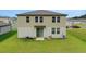 A view of the back of a two-story home showing the backyard with a lawn and sliding glass door at 203 Lovely Ct, Plant City, FL 33566