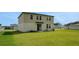 Large grassy backyard, complemented by the home's exterior with an access door and large windows on the second story at 203 Lovely Ct, Plant City, FL 33566
