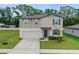 A two-story home with a two-car garage and modern design, surrounded by a lush green lawn and vibrant landscaping at 203 Lovely Ct, Plant City, FL 33566
