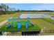 Community playground with slides and play structures on artificial turf and a view of the pond at 203 Lovely Ct, Plant City, FL 33566