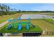 Community playground with slides and play structures on artificial turf and a view of the pond at 203 Lovely Ct, Plant City, FL 33566