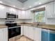 Bright kitchen with stainless steel appliances, granite countertops, white cabinets, and a subway tile backsplash at 4921 Marlin Dr, New Port Richey, FL 34652