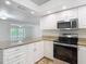Bright kitchen featuring granite countertops, stainless appliances, white cabinets, and an open view to the living area at 4921 Marlin Dr, New Port Richey, FL 34652