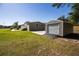 Backyard featuring home, driveway, shed with roll-up door, and green grass at 8318 Franklin Rd, Plant City, FL 33565