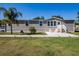Inviting single-story home with neutral siding, palm tree, manicured lawn, and cozy front porch adorned with rocking chairs at 8318 Franklin Rd, Plant City, FL 33565
