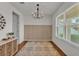 Light-filled dining room with hardwood floors, modern chandelier, and wainscoting detail at 9015 Spruce Creek Cir, Riverview, FL 33578