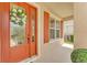 Inviting front entrance with a wreath, orange door, and window with shutters at 9015 Spruce Creek Cir, Riverview, FL 33578